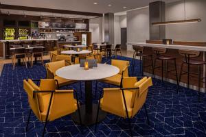 a restaurant with yellow chairs and tables and a bar at Courtyard by Marriott San Angelo in San Angelo