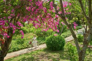 una mujer montando una bicicleta en un parque con flores rosas en Fleur de Lys Resort & Spa Long Hai, en Long Hai