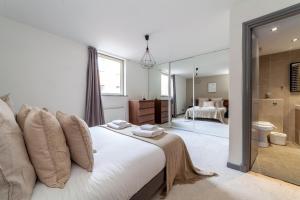 a bedroom with a large white bed and a bathroom at The Wapping Villas in London