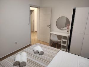 a white bedroom with a bed with towels on it at Apartman Smokva in Kumbor