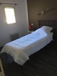 Una cama con sábanas blancas y una ventana en un dormitorio en Agréable maisonnette de 45m2, en Gallargues-le-Montueux