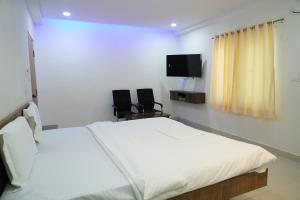 a bedroom with a bed and two chairs and a tv at 5 STAR GRAND- PREMIUM in Shamshabad
