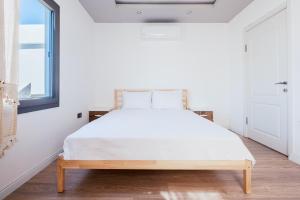 a bedroom with a large bed with white sheets and a window at Chic Flat w Balcony 3 min to Beach in Bodrum in Bodrum City