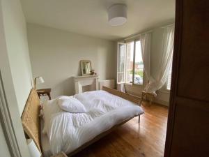 Schlafzimmer mit einem Bett mit weißer Bettwäsche und einem Fenster in der Unterkunft Le presbytère in Cayeux-sur-Mer
