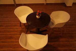 una mesa con sillas blancas y un jarrón con flores. en 5 STAR GRAND- PREMIUM en Shamshabad