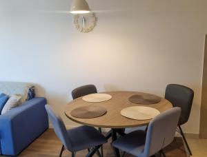 stół z 4 krzesłami i niebieską kanapą w obiekcie Doxa M Apartments w mieście Herceg Novi