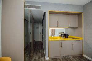 una cocina con encimera amarilla y armarios blancos en Alliance Palace Aparthotel, en Batumi