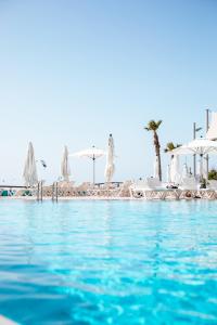 a swimming pool with white chairs and umbrellas at Daniel Herzliya Hotel in Herzelia 