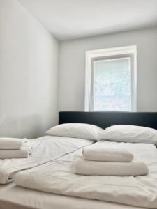 Una cama con sábanas blancas y una ventana en una habitación en ZARA APARTMENTS, en Koper