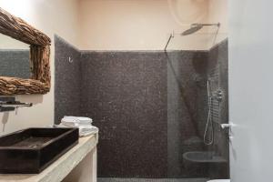 La salle de bains est pourvue d'une douche et d'un lavabo noir. dans l'établissement Wp Relais apartments, à Diso