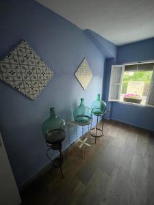 tres jarrones verdes sentados en mesas en una habitación azul en Casa Rural Las Raíces, Sierra de San Vicente en San Román