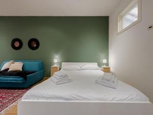 ein Schlafzimmer mit einem weißen Bett und einem blauen Sofa in der Unterkunft Realkasa Belfiore Apartment in Bologna