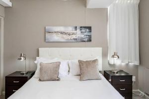 a bedroom with a large white bed with two lamps at 801 Infinity 2 Bedroom Beachfront Apartment in Cape Town +27 photos