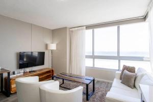 a living room with white chairs and a flat screen tv at 801 Infinity 2 Bedroom Beachfront Apartment in Cape Town