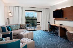 a hotel room with a couch and a desk with a computer at Courtyard by Marriott Fort Lauderdale Coral Springs in Coral Springs