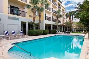 una piscina frente a un edificio con palmeras en Courtyard by Marriott Fort Lauderdale Coral Springs, en Coral Springs