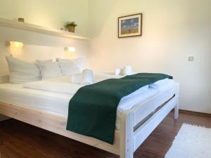 Una cama blanca con una manta verde. en Haus Land & Meer FeWo14, en Cuxhaven