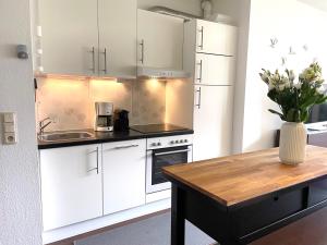 Una cocina con gabinetes blancos y una mesa de madera. en Haus Land & Meer FeWo14, en Cuxhaven 7 fotos más