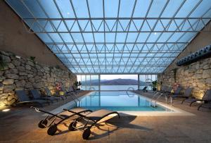a swimming pool with chairs and a large glass ceiling at Parador de Lorca in Lorca