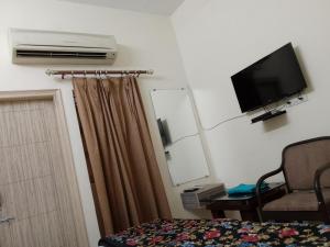 1 dormitorio con cama, espejo y TV en The Royal Elite Guest House, en Jalandhar
