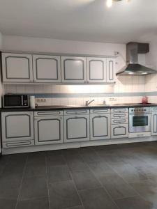 a large kitchen with white cabinets and appliances at Wohnung am Waldrand in Melle