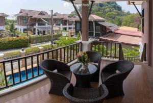 a balcony with chairs and a table with a view of a pool at Nadia's Ao Nang Pool Villa in Ban Chong Phli