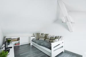 Cette chambre blanche dispose d'un banc avec des oreillers. dans l'établissement L'évasion - Charmant appt pour 4, à La Bresse