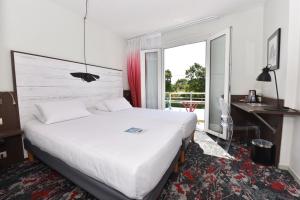 ラ・ロシェルにあるHôtel Kyriad La Rochelle Centre Villeのベッド、デスク、窓が備わるホテルルームです。