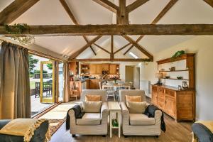 una sala de estar de planta abierta con techos de madera y una cocina. en Finest Retreats - The Burrow at Conygre Farm en Pewsey