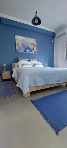 a bedroom with a large bed with a blue wall at Velvet new apt in Ilissia in Athens