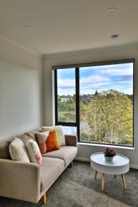 a living room with a couch and a large window at Amazing the Waikato River-View Brand New Villa with 4 bedrooms in Hamilton