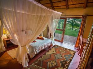 a bedroom with a canopy bed and a window at Kayova River Lodge in Ndiyona