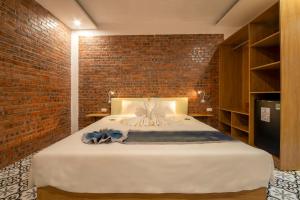 a bedroom with a large white bed with a brick wall at Hoi An Golden Bamboo An Bang Beach Villa & Spa in Hoi An