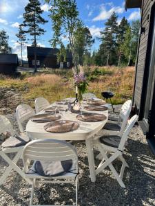 Fjällstugan i Funäsdalen في فوناسدالاين: طاولة بيضاء عليها كراسي بيضاء وورود