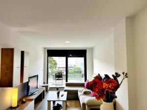 a living room with a couch and a vase of flowers at Holibai, Bon Xeito, Moderno y Cómodo Apartamento in Baiona