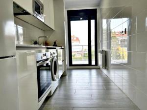 een keuken met een wasmachine en droger naast een deur bij Holibai, Bon Xeito, Moderno y Cómodo Apartamento in Baiona