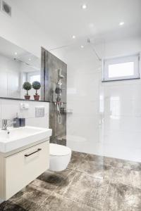 a white bathroom with a toilet and a shower at Apartment NeWA in Gąski