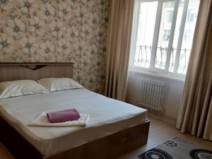 Un dormitorio con una cama con una toalla morada. en Elite Apartment in street Orozbekova 2 en Bishkek