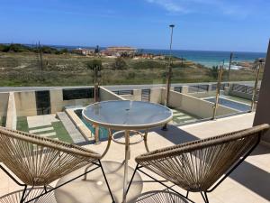 a patio with a glass table and two chairs at Duplex con piscina individual y vistas al mar en Torrevieja in Torrevieja