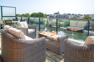 un patio con sedie in vimini e un tavolo sul balcone. di Au Fil de L'Erdre - Spacieux appt avec terrasse a Nantes