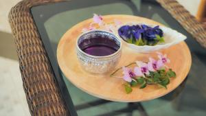 a table with a plate of purple and purple flowers at Siam Avari Hotel, Chiang Rai in Chiang Rai