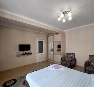 una camera con un letto e due sedie e una televisione di Elite Apartment in street Orozbekova 2 a Bishkek