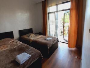 Cette chambre comprend deux lits et une porte donnant sur un balcon. dans l'établissement Guest House Dimitri, à Chakvi