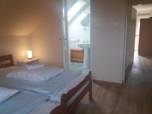 a bedroom with two beds and a bathroom with a sink at Egervári Béres Vendégház-Tetőtéri apartman in Egervár