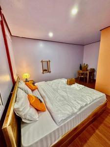 a bedroom with a large bed with white sheets and yellow pillows at Heaven Guesthouse in Pakse