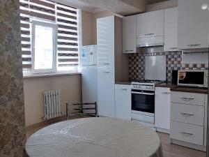 cocina con armarios blancos, mesa y ventana en Elite Apartment in street Orozbekova 2 en Bishkek