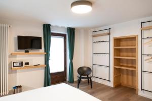 a bedroom with a bed and a television and a chair at Hotel SALEI in Ghigo