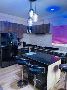 a kitchen with black counter tops and bar stools at Dsmarts apartments in Benin City
