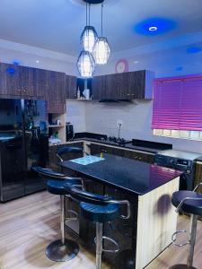 a kitchen with black counter tops and bar stools at Dsmarts apartments in Benin City