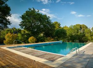 a swimming pool with a wooden deck next to a wooden floor at Domaine de la Marie dans le Luberon in Peypin-dʼAigues